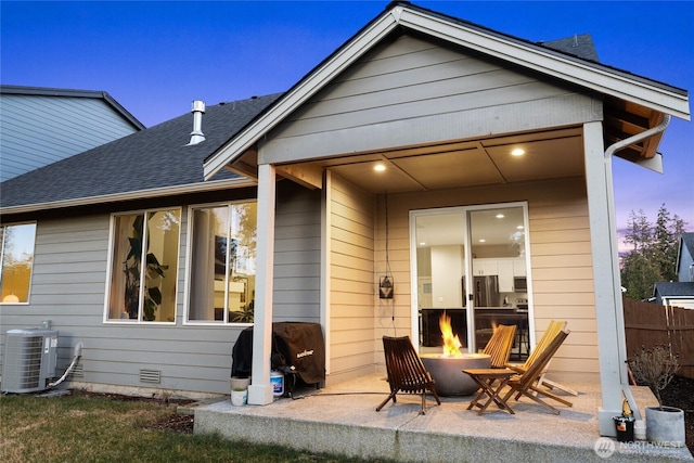 back house at dusk featuring a patio, central AC unit, and a fire pit