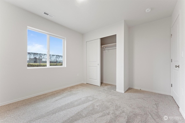 unfurnished bedroom featuring a closet and light colored carpet