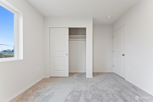 unfurnished bedroom with a closet and light colored carpet