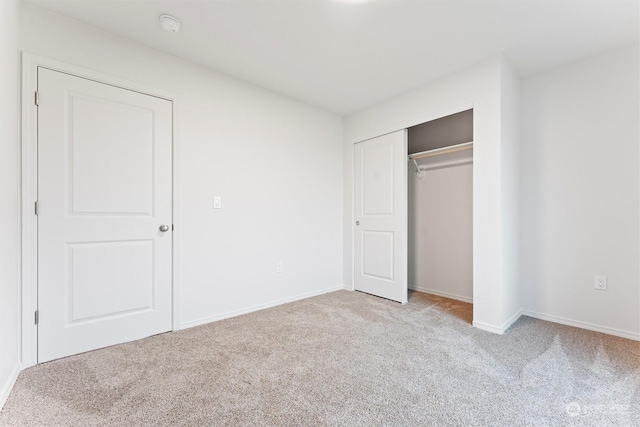 unfurnished bedroom featuring light carpet and a closet