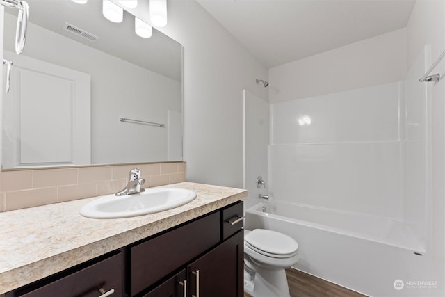 full bathroom featuring hardwood / wood-style floors, shower / bathtub combination, vanity, toilet, and decorative backsplash