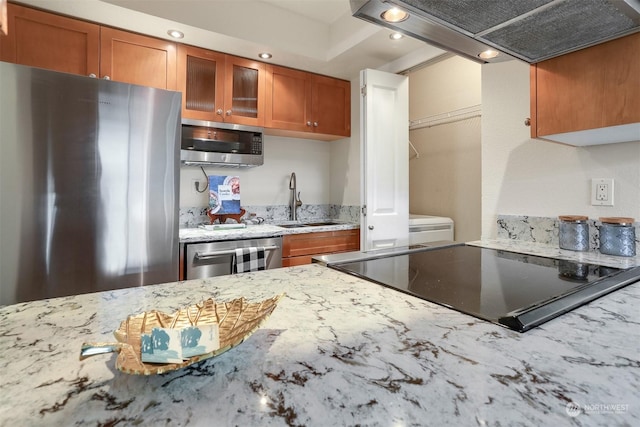 kitchen with premium range hood, stainless steel appliances, sink, and light stone counters