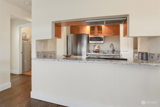 kitchen featuring sink, strapped water heater, stainless steel appliances, dark hardwood / wood-style floors, and light stone countertops