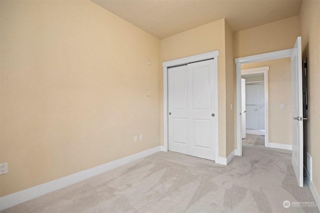 unfurnished bedroom with light colored carpet and a closet