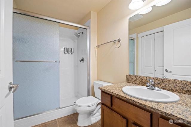 bathroom with vanity, toilet, a shower with shower door, and tile patterned flooring