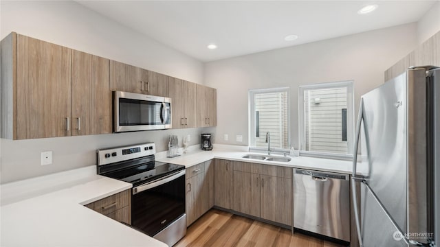 kitchen featuring stainless steel appliances, sink, and light hardwood / wood-style flooring