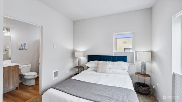 bedroom with connected bathroom and hardwood / wood-style floors