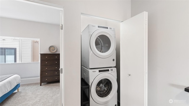 clothes washing area with light colored carpet and stacked washer / dryer