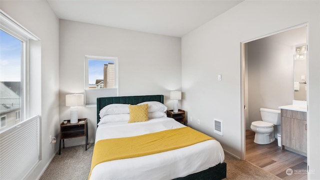 bedroom featuring connected bathroom and hardwood / wood-style flooring