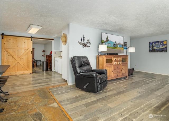 living room with hardwood / wood-style floors, a barn door, and a textured ceiling