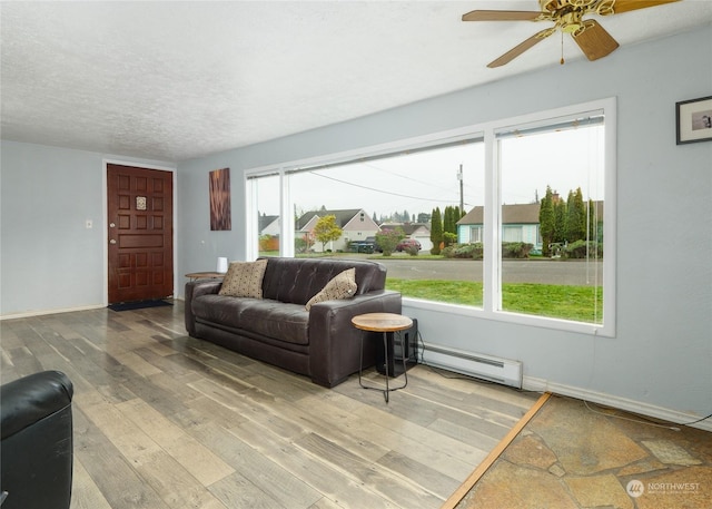 living room featuring ceiling fan, hardwood / wood-style floors, a textured ceiling, and baseboard heating