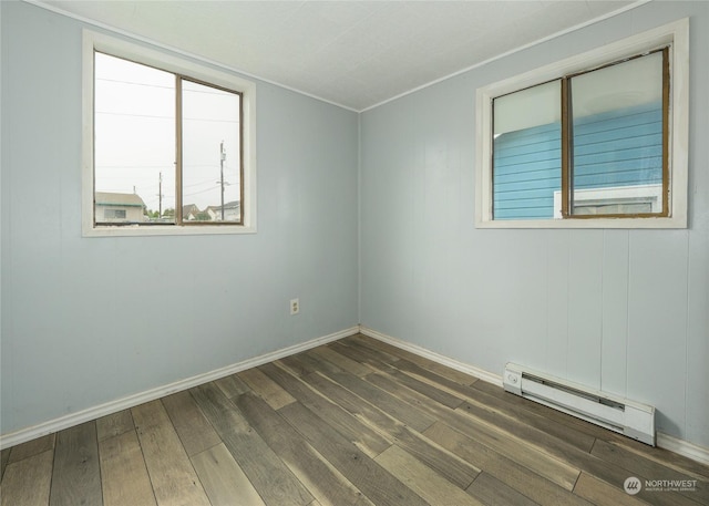 unfurnished room featuring a baseboard heating unit and dark hardwood / wood-style floors