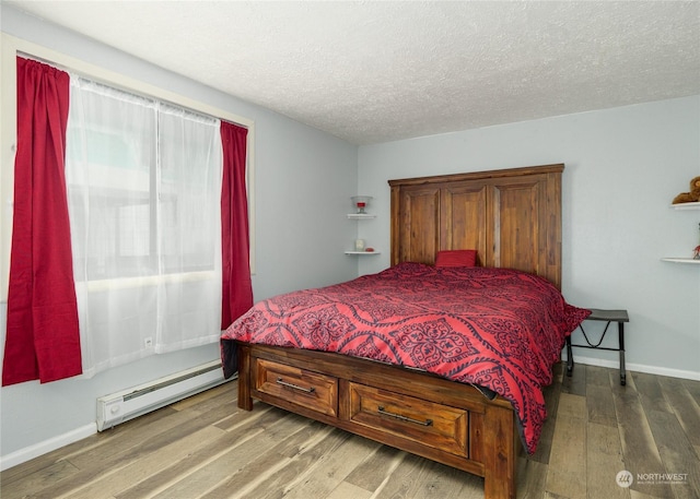 bedroom with a baseboard heating unit, hardwood / wood-style flooring, and a textured ceiling