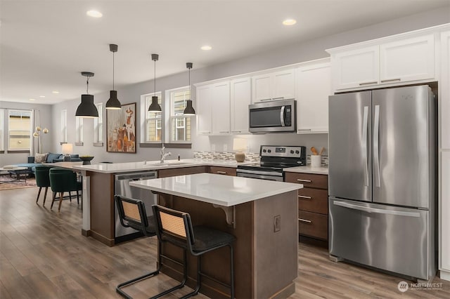 kitchen featuring white cabinetry, stainless steel appliances, a breakfast bar, and a kitchen island