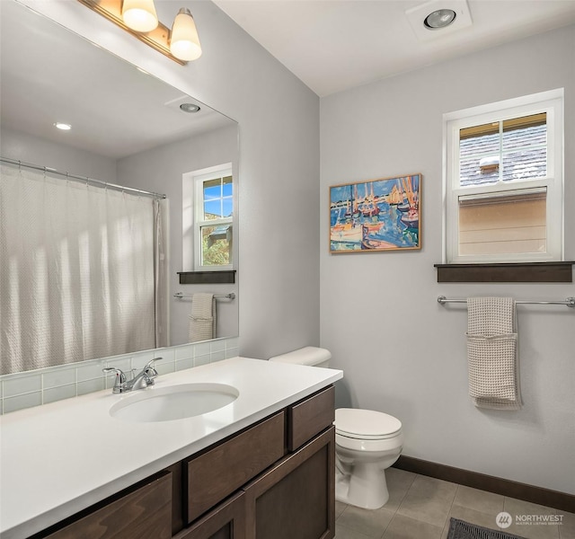 bathroom featuring vanity, plenty of natural light, tile patterned floors, and toilet