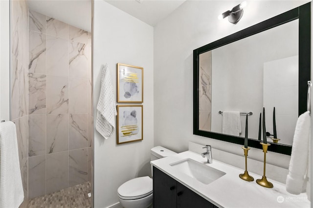 bathroom with vanity, toilet, and tiled shower