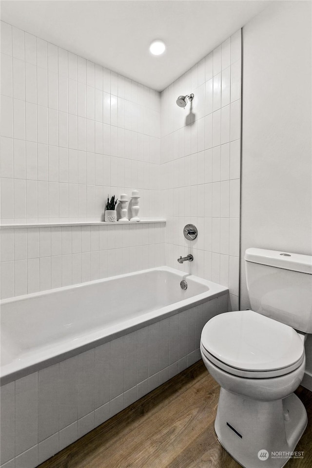 bathroom with hardwood / wood-style floors, tiled shower / bath combo, and toilet