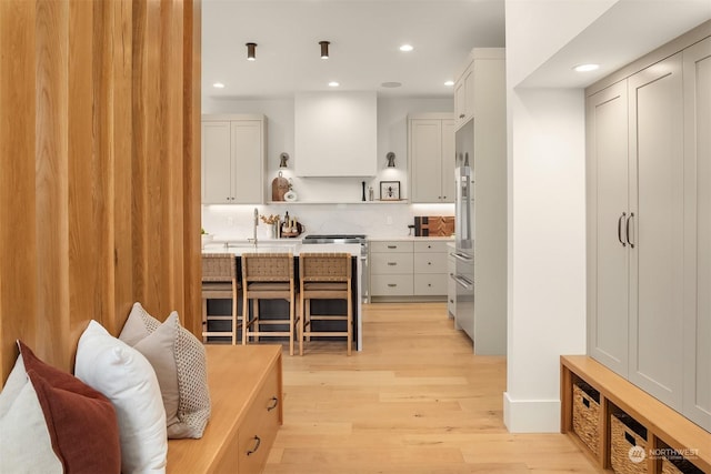 kitchen with white cabinetry, decorative backsplash, light hardwood / wood-style flooring, and a kitchen bar