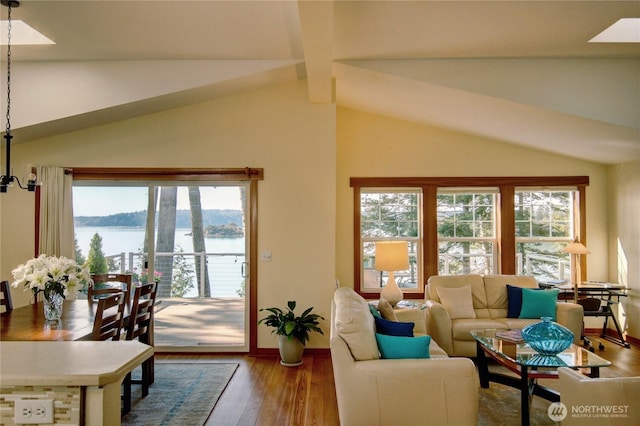 living area featuring vaulted ceiling with beams, wood finished floors, a water view, and baseboards