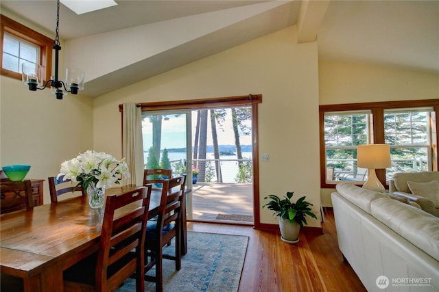 dining room featuring baseboards, lofted ceiling, an inviting chandelier, and wood finished floors