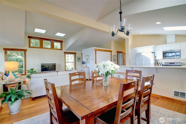 dining area featuring light wood finished floors, visible vents, lofted ceiling with skylight, a chandelier, and recessed lighting