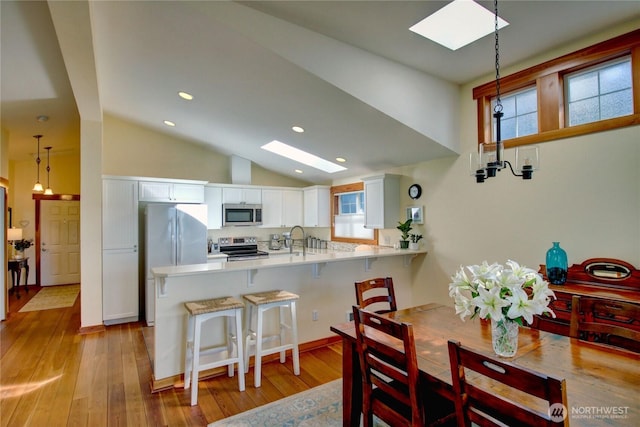 dining area featuring lofted ceiling with skylight, recessed lighting, and light wood-style floors