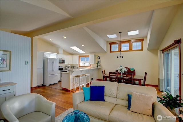 living area with lofted ceiling with skylight, recessed lighting, and wood finished floors