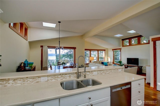 kitchen featuring vaulted ceiling with beams, open floor plan, dishwasher, white cabinets, and a sink