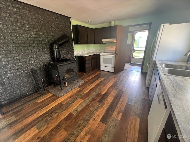 kitchen with white appliances, under cabinet range hood, dark wood-style flooring, a sink, and light countertops