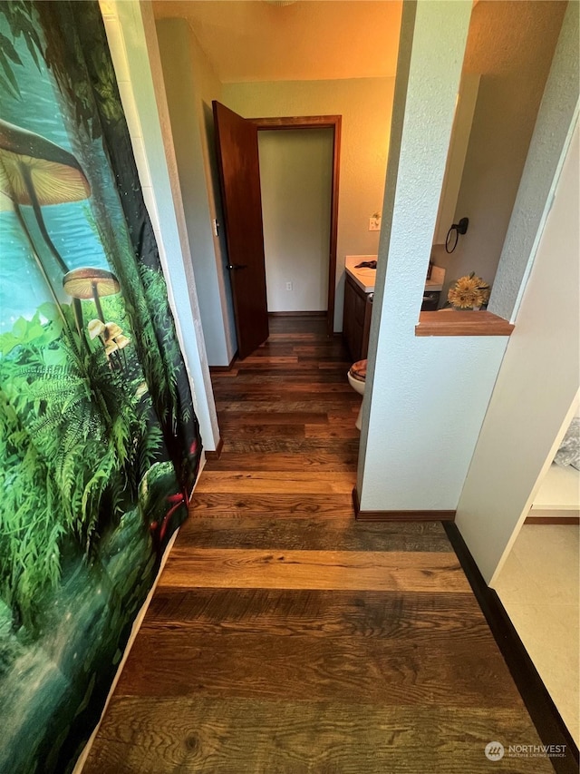 hallway featuring baseboards and wood finished floors
