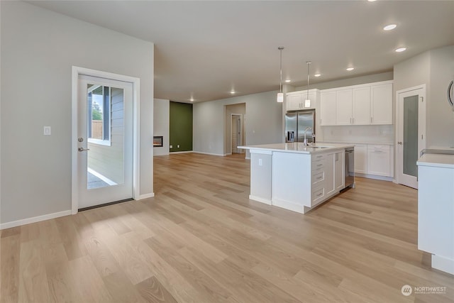 kitchen with sink, white cabinetry, a center island with sink, appliances with stainless steel finishes, and pendant lighting