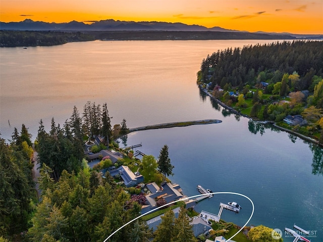 aerial view at dusk featuring a water and mountain view