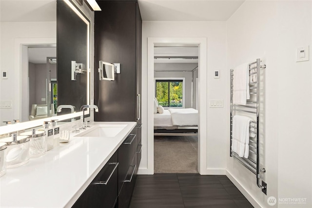 ensuite bathroom featuring baseboards, vanity, and connected bathroom