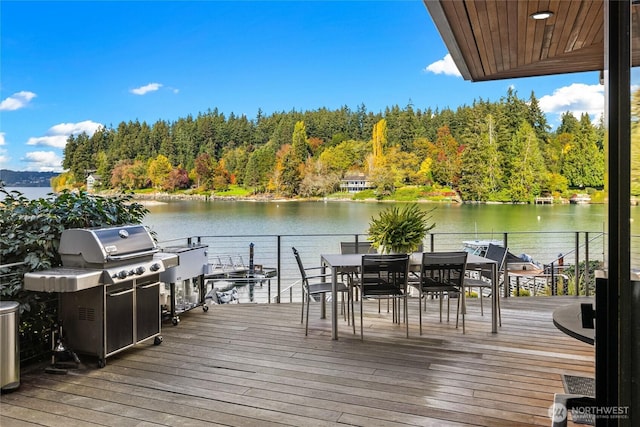 view of dock with a view of trees, outdoor dining space, and a water view