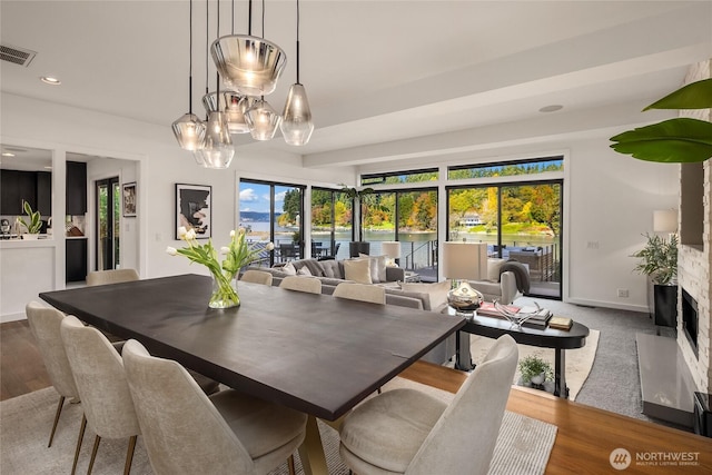 dining space featuring a fireplace, visible vents, baseboards, and wood finished floors