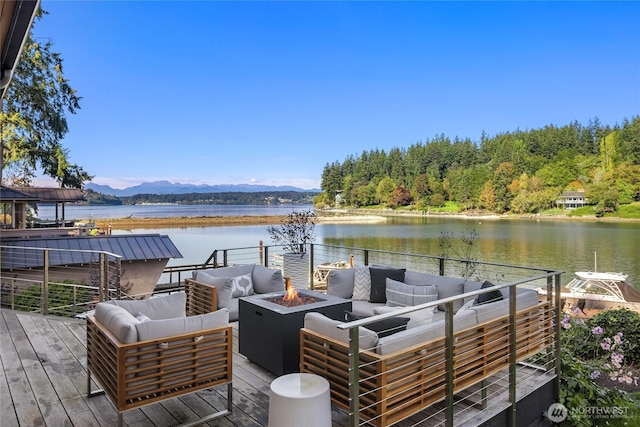 wooden deck featuring an outdoor living space with a fire pit and a water and mountain view