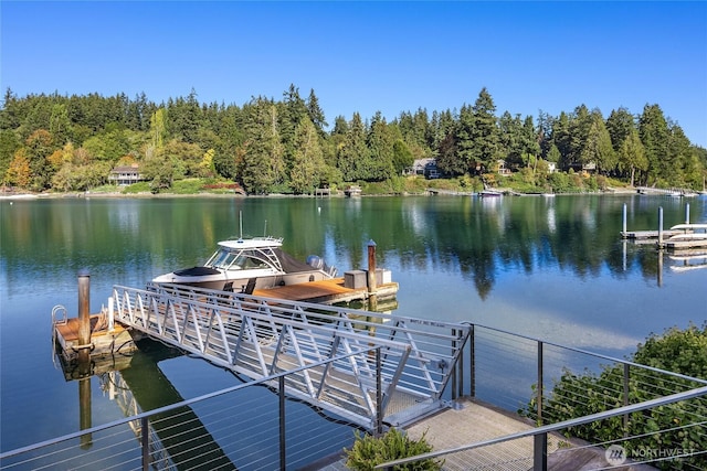 view of dock with a wooded view and a water view