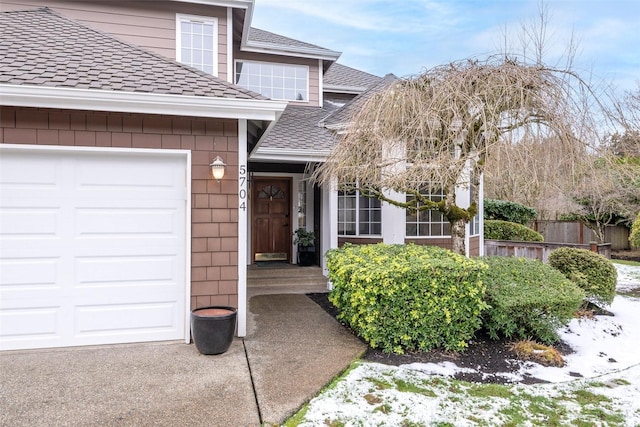 snow covered property entrance featuring a garage