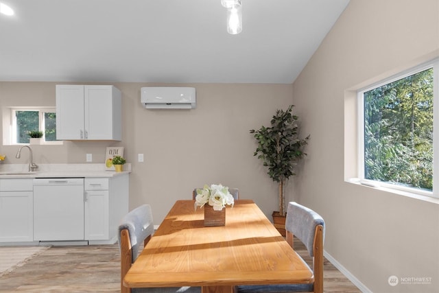 dining space with lofted ceiling, sink, a wall unit AC, and light hardwood / wood-style flooring