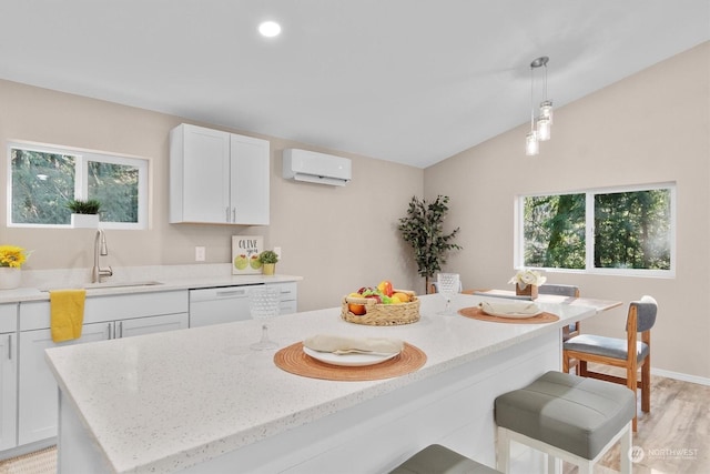 kitchen featuring sink, dishwasher, white cabinets, decorative light fixtures, and an AC wall unit