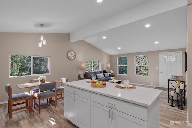 kitchen with vaulted ceiling with beams, decorative light fixtures, light hardwood / wood-style flooring, and white cabinets