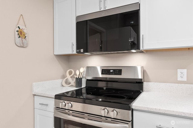 kitchen featuring electric stove, light stone counters, and white cabinets