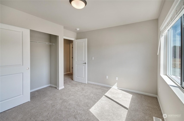 unfurnished bedroom with light carpet and a closet