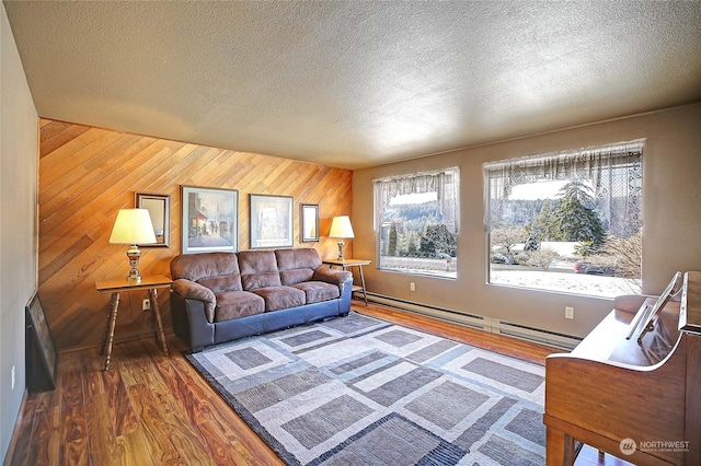 living room featuring baseboard heating, wood-type flooring, wooden walls, and a textured ceiling