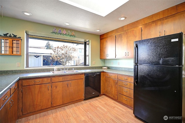 kitchen with light hardwood / wood-style floors, sink, a textured ceiling, and black appliances