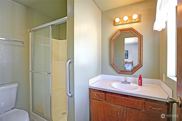 bathroom featuring vanity, an enclosed shower, and toilet