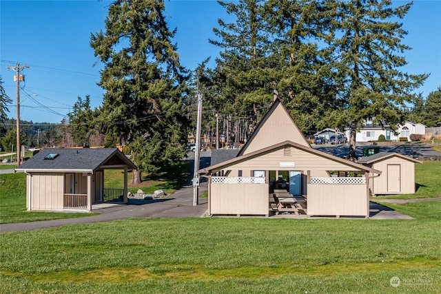 rear view of house with a storage shed and a yard