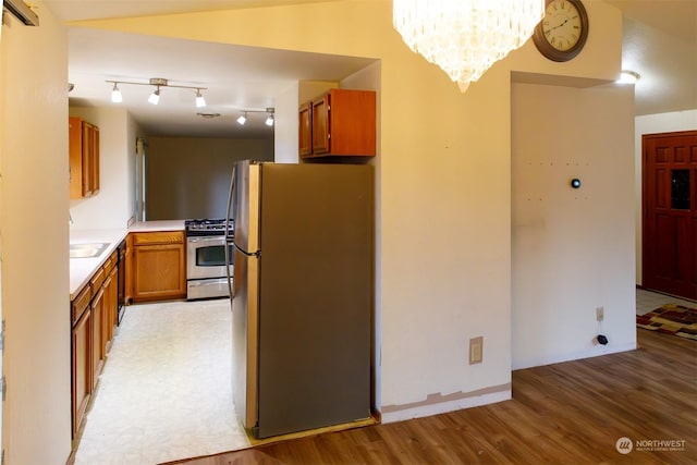 kitchen with appliances with stainless steel finishes, track lighting, a chandelier, and light hardwood / wood-style flooring