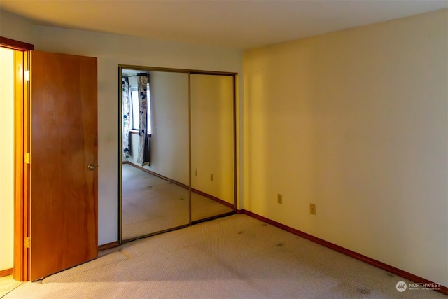 unfurnished bedroom featuring light colored carpet and a closet