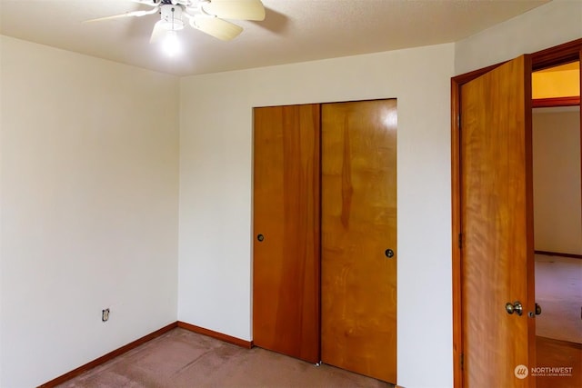 unfurnished bedroom featuring ceiling fan, light carpet, and a closet